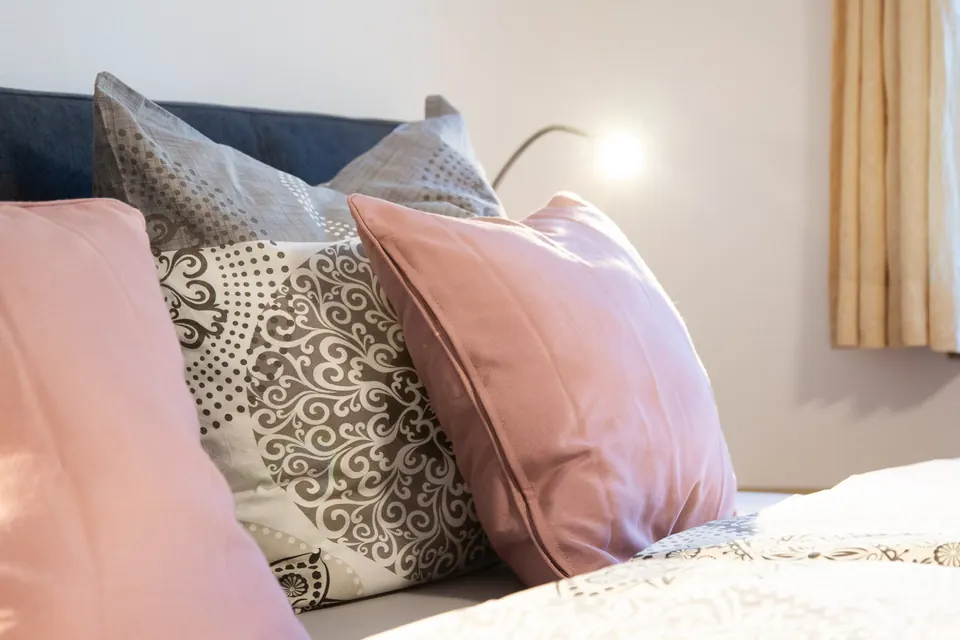 Kissen in Altrosa und Grau auf dem Bett