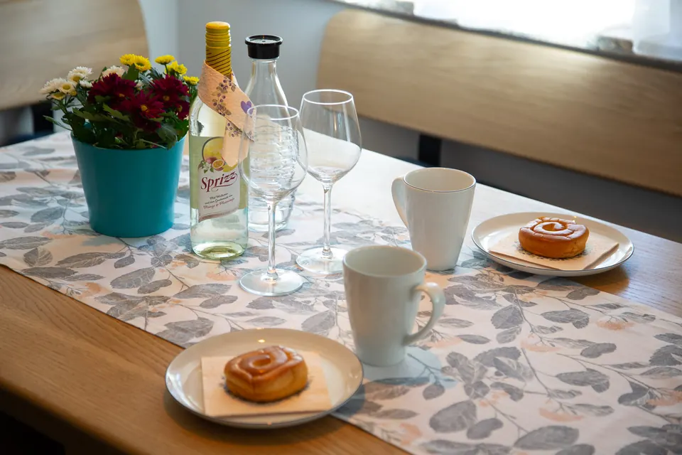 Gedeckter Tisch mit Blumen, Kaffeetassen und Gebäck